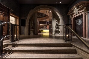 A grand staircase leading to a reception area with a modern interior, stone walls, and a statue. - Best Western Premier Hotel Rebstock (Würzburg)