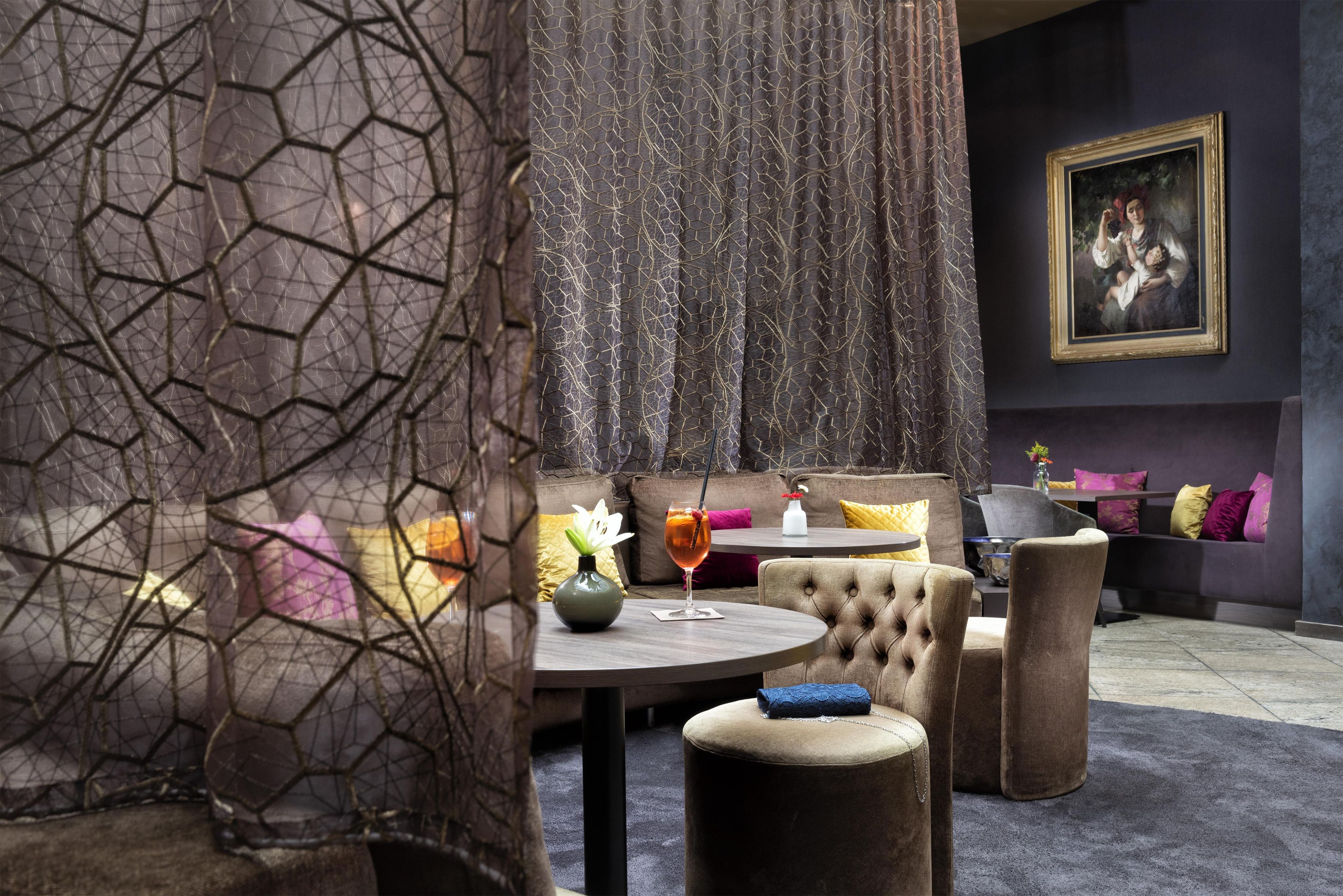 A modern interior with a round table, cushioned seating, and a decorative curtain.