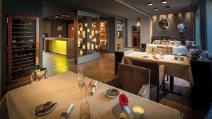 A restaurant with tables set for dining, a wine rack, and a bar area.