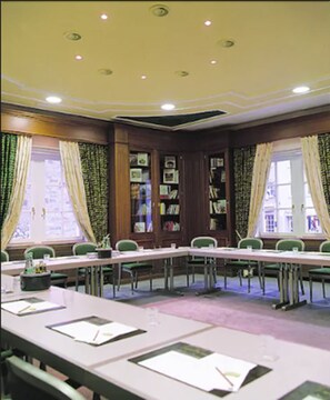 A conference room with a long table, chairs, and bookshelves.