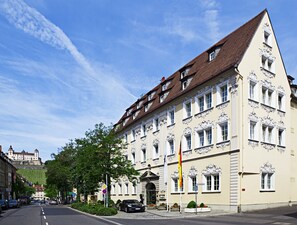 A historic building with ornate architecture, a flagpole, and a street view.