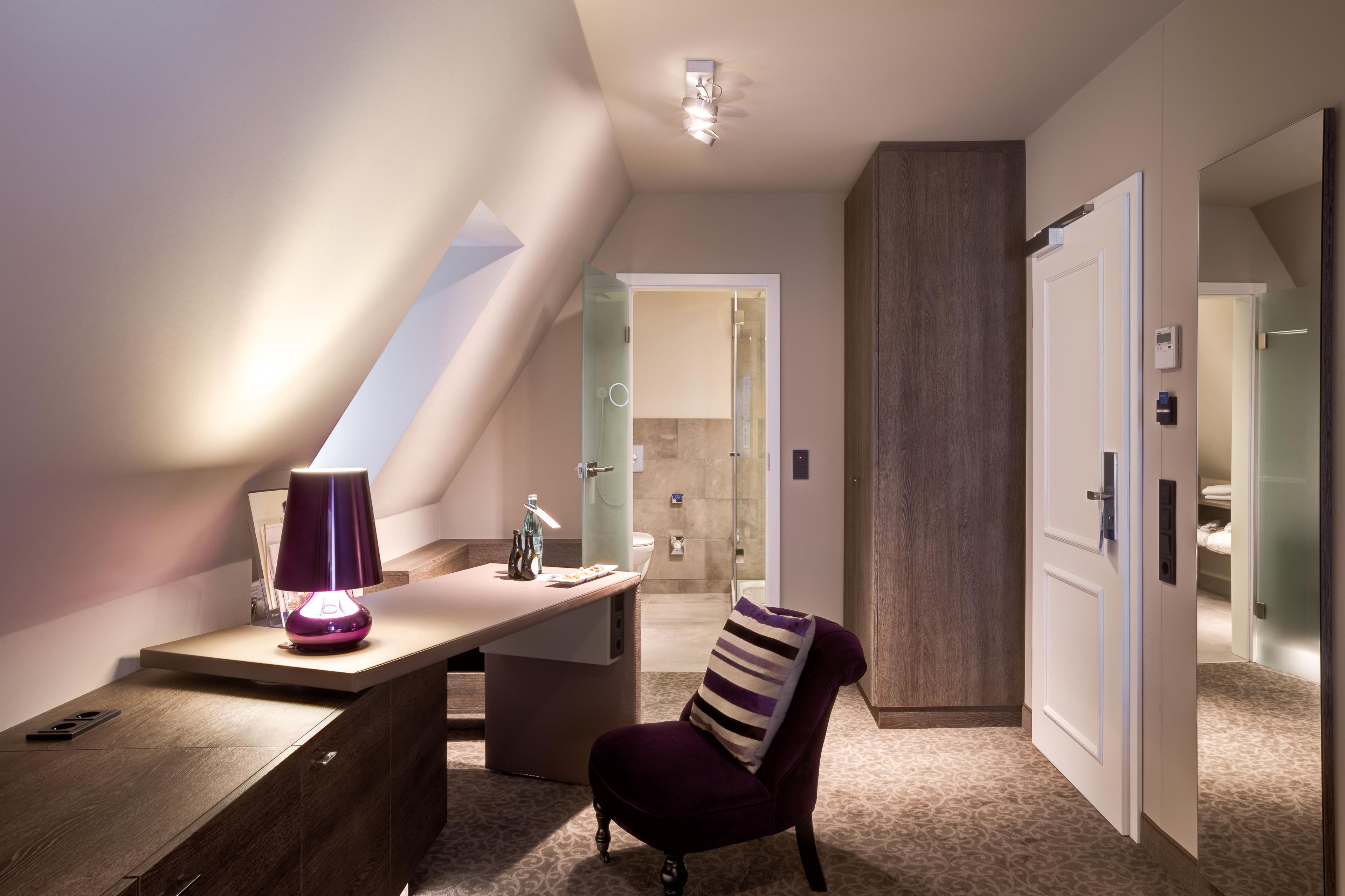 A modern bedroom with a desk, chair, and a glass shower enclosure.