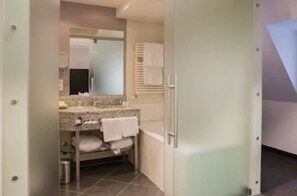 A bathroom with a granite countertop, a mirror, a towel rack, and a shower area.