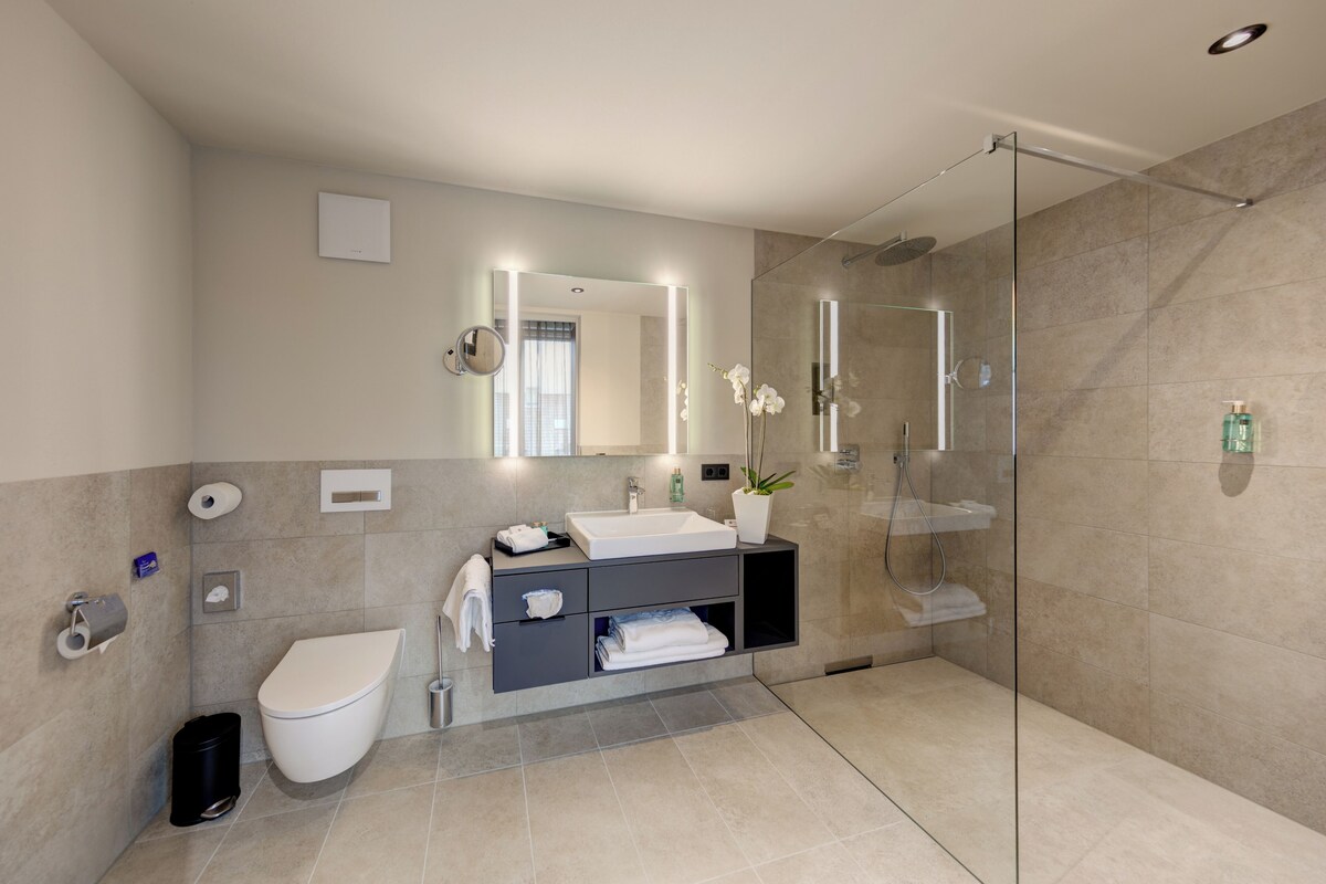 A modern bathroom with a glass-enclosed shower, a white sink, and a toilet.