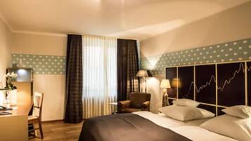 A hotel room with a bed, a desk, a chair, and a window with curtains.
