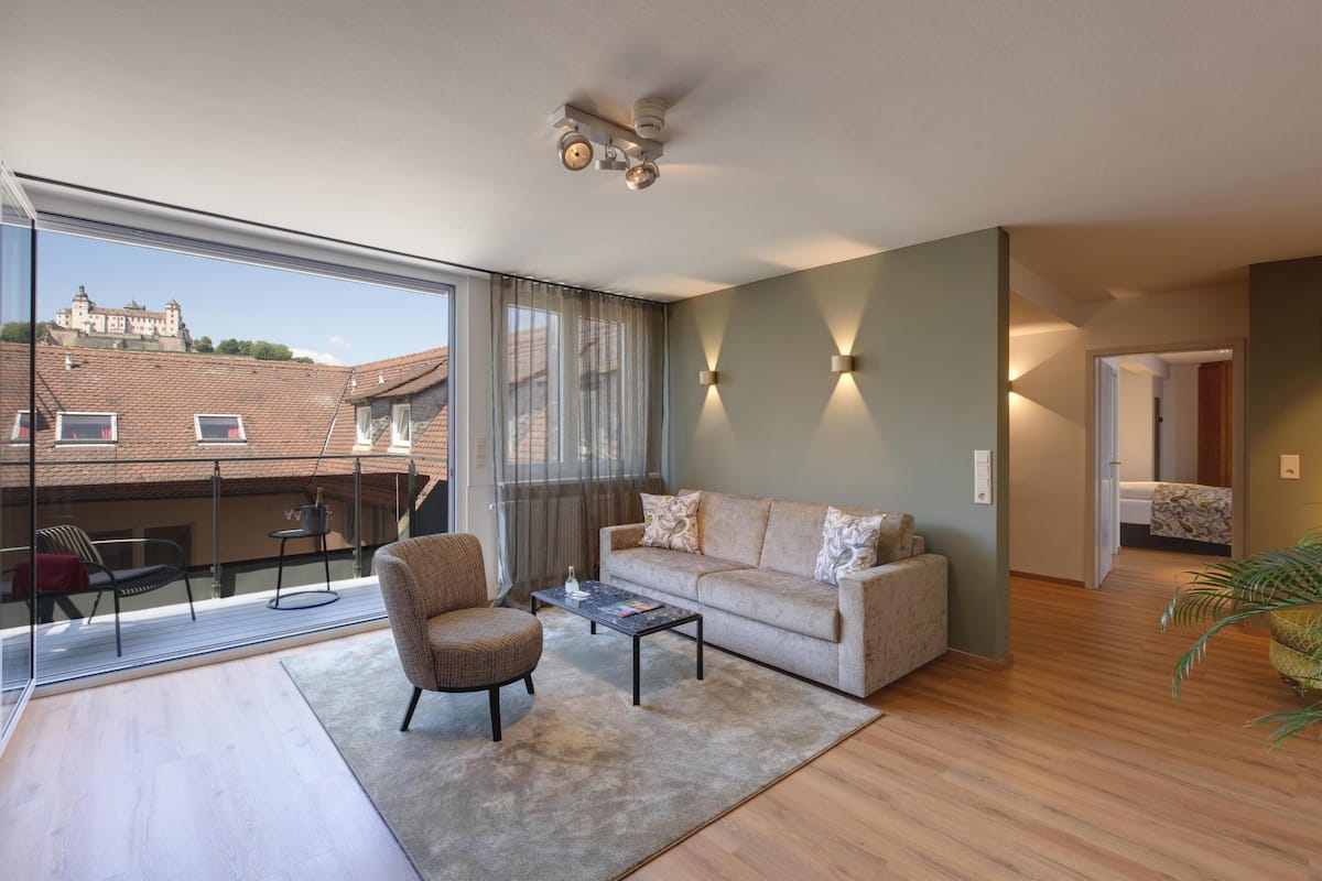 A spacious living room with a large window, a sofa, a coffee table, and a chair.