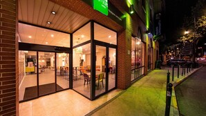 A hotel with a glass facade, a green sign, and a brick exterior. - ibis Styles Perpignan Centre Gare (Perpignan)
