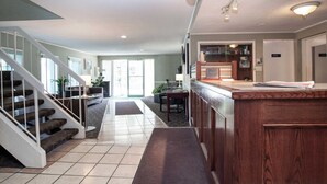 A spacious living area with a staircase, a kitchen area, and a reception desk.