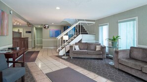 A spacious living room with a staircase, a sofa, a coffee table, and a dining area. - Sandman Inn Cache Creek (Cache Creek)