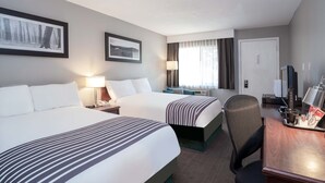A hotel room with two beds, a desk, a chair, a television, and a window with curtains. - Sandman Inn Cache Creek (Cache Creek)