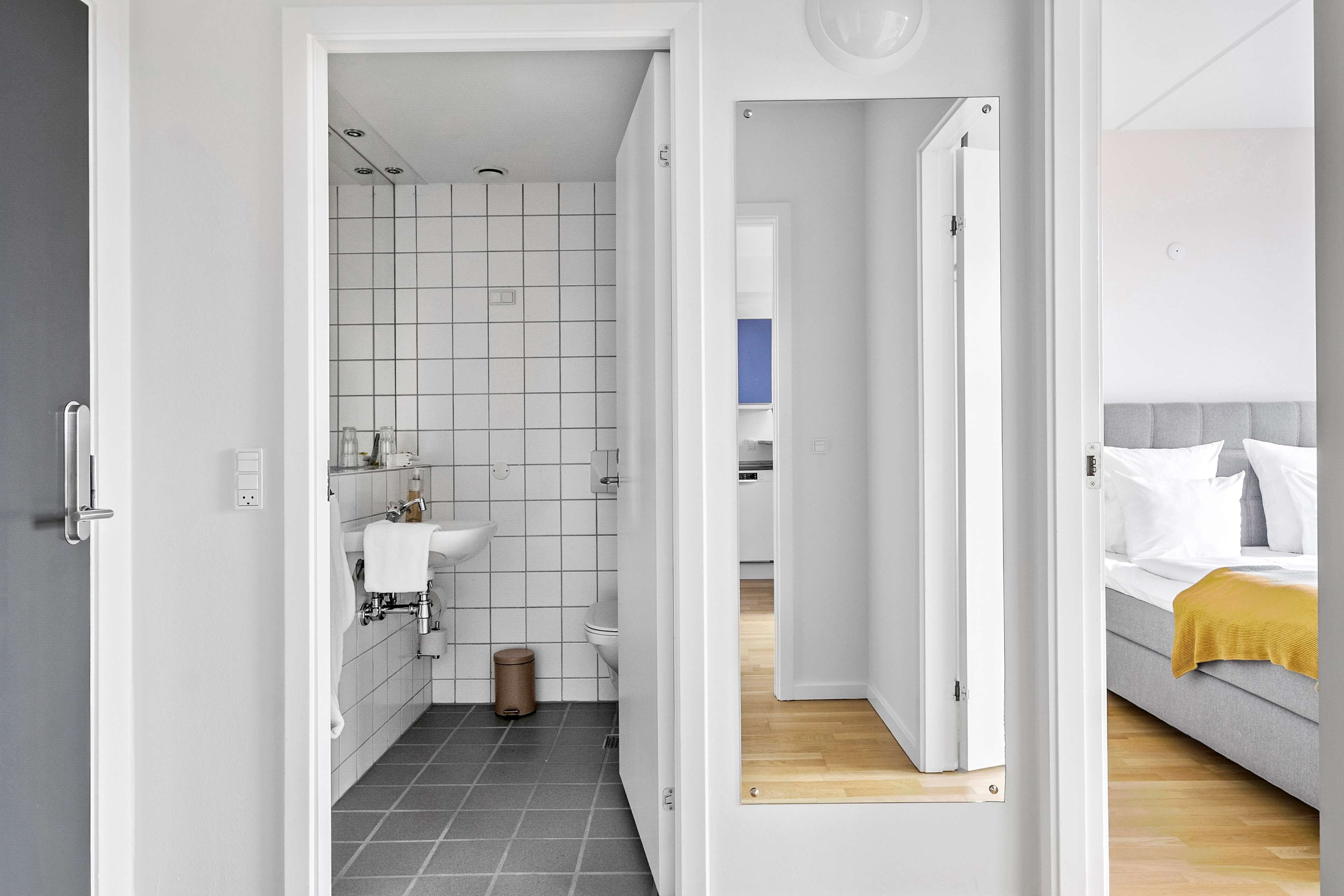 Un baño moderno con un lavamanos blanco, inodoro y paredes con azulejos.