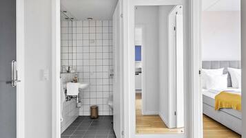 Un baño moderno con un lavamanos blanco, inodoro y paredes con azulejos.