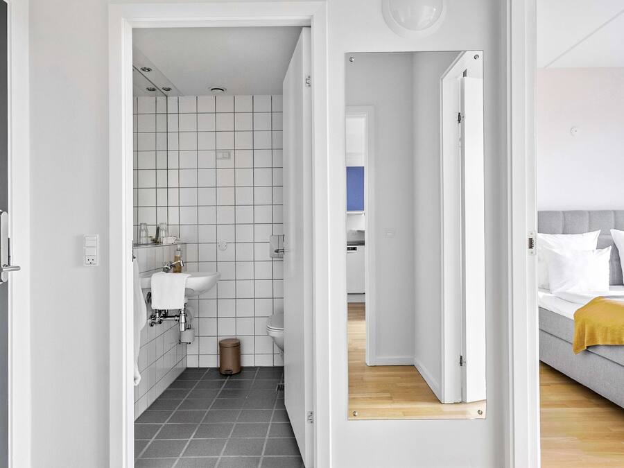 Un baño moderno con un lavamanos blanco, inodoro y paredes con azulejos.
