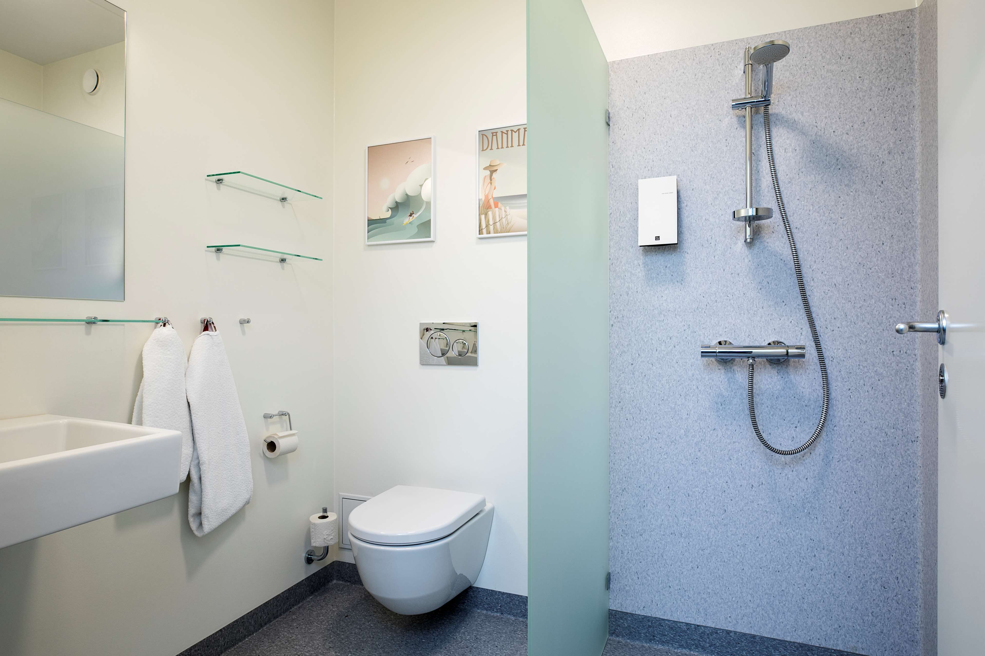 Une salle de bain moderne avec un lavabo, des toilettes, des étagères en verre et une douche.
