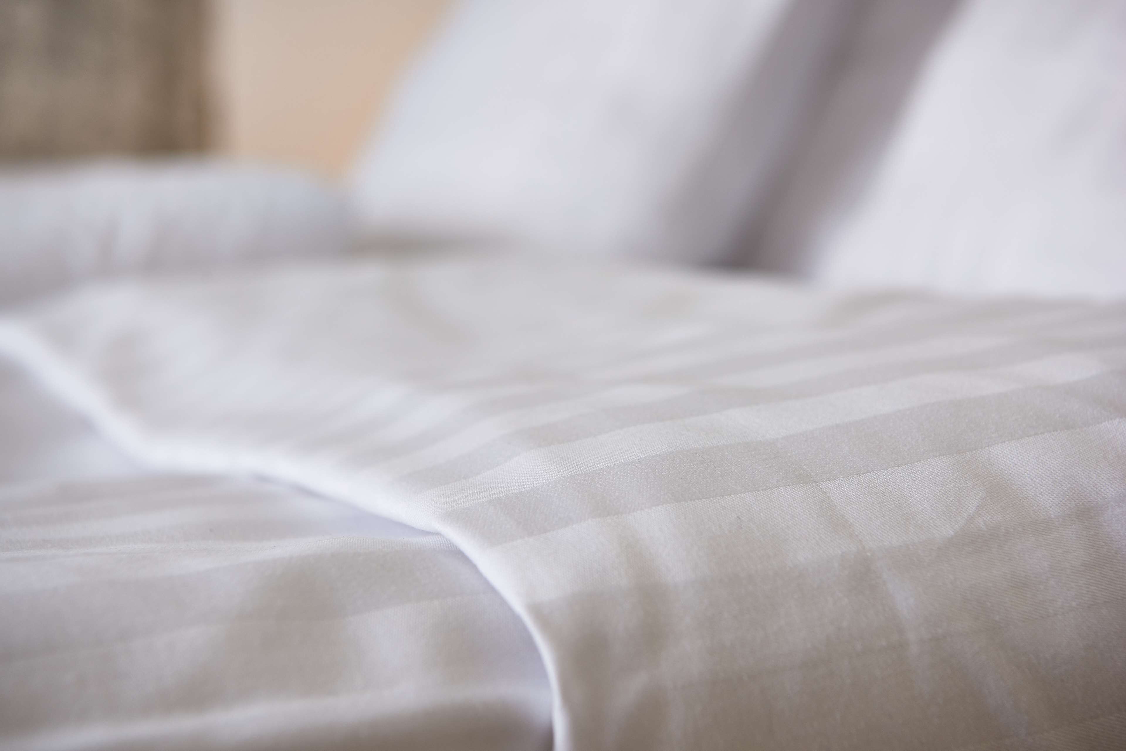 A close-up of a bed with a white and gray striped bedding.