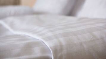 A close-up of a bed with a white and gray striped bedding.