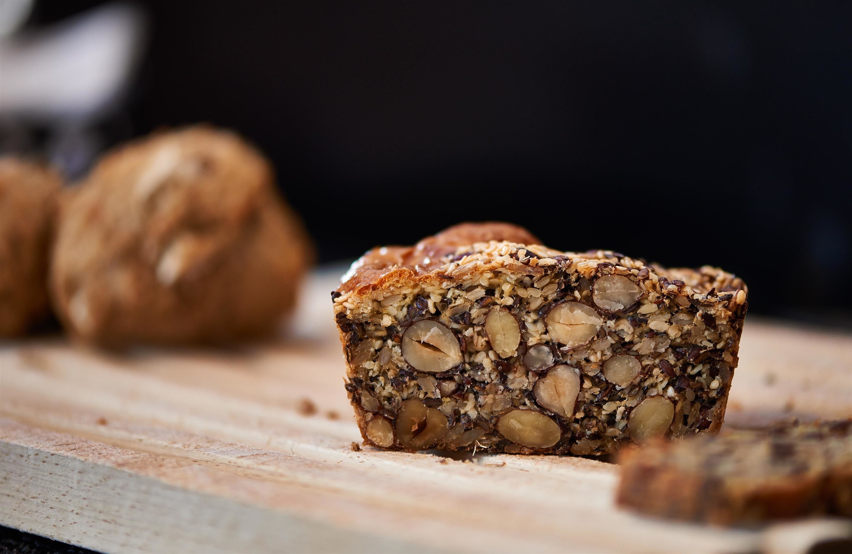 A close-up of a nut and seed loaf on a wooden board.