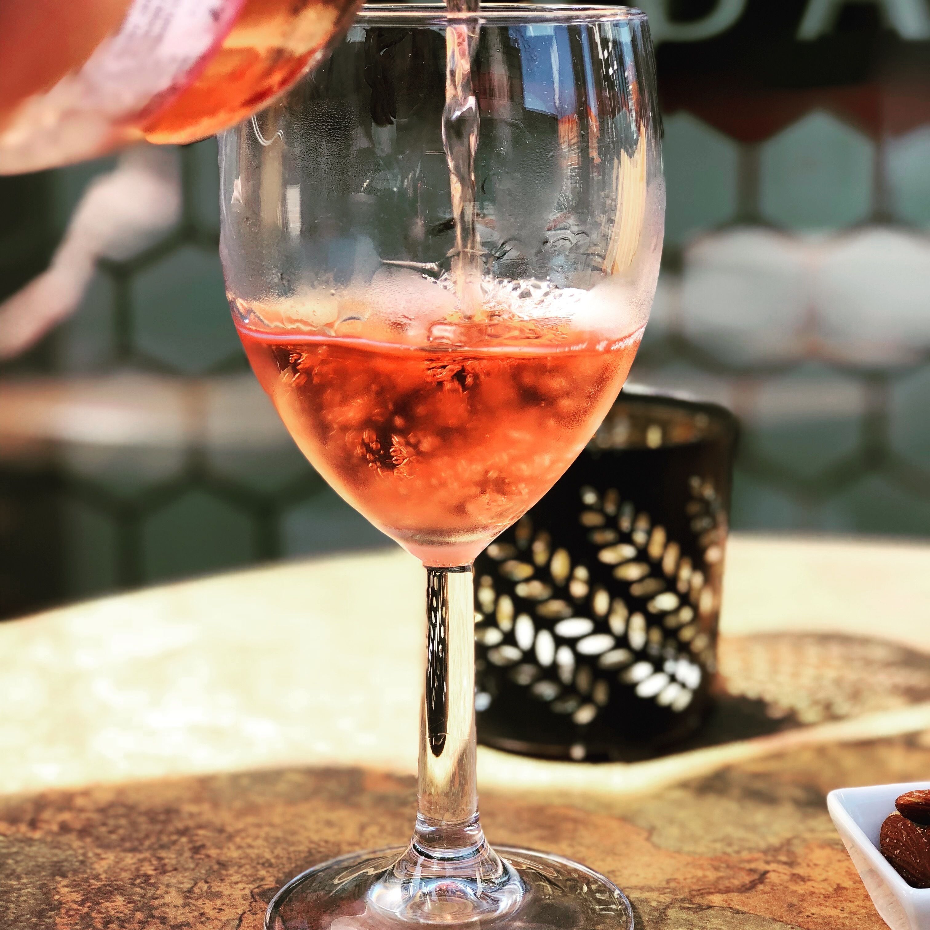 Un vaso de bebida rosada sobre una mesa con un fondo de diseño hexagonal.