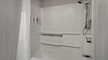 A modern bathroom with a shower, grab bars, and a toilet.