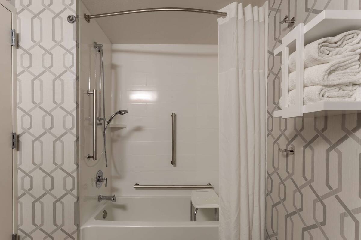 A modern bathroom with a shower, bathtub, and a towel rack.