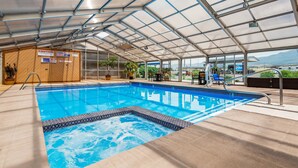 An indoor swimming pool with a glass ceiling, surrounded by lounge chairs and potted plants. - Best Western Paradise Inn & Resort (Fillmore)