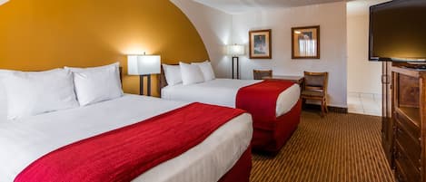 Une chambre d’hôtel avec deux lits, une télévision, un bureau et une chaise.