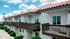 A row of white brick buildings with red-tiled roofs and balconies.
