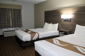 A hotel room with two beds, a large window with curtains, a wall-mounted TV, and a bedside table.