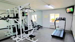 A gym with exercise equipment, a treadmill, and a TV on the wall.