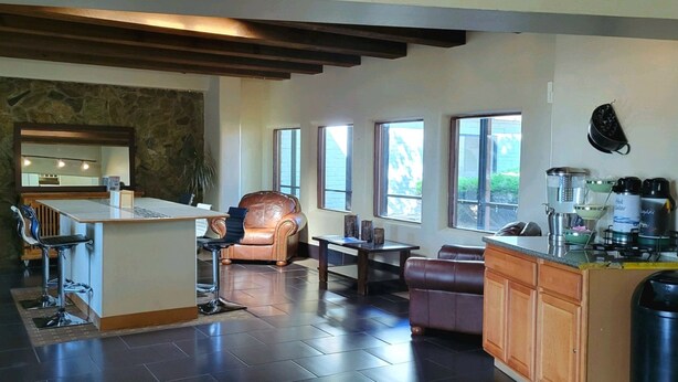 A modern kitchen with a stone wall, a bar area, and a seating area with a leather chair and sofa.
