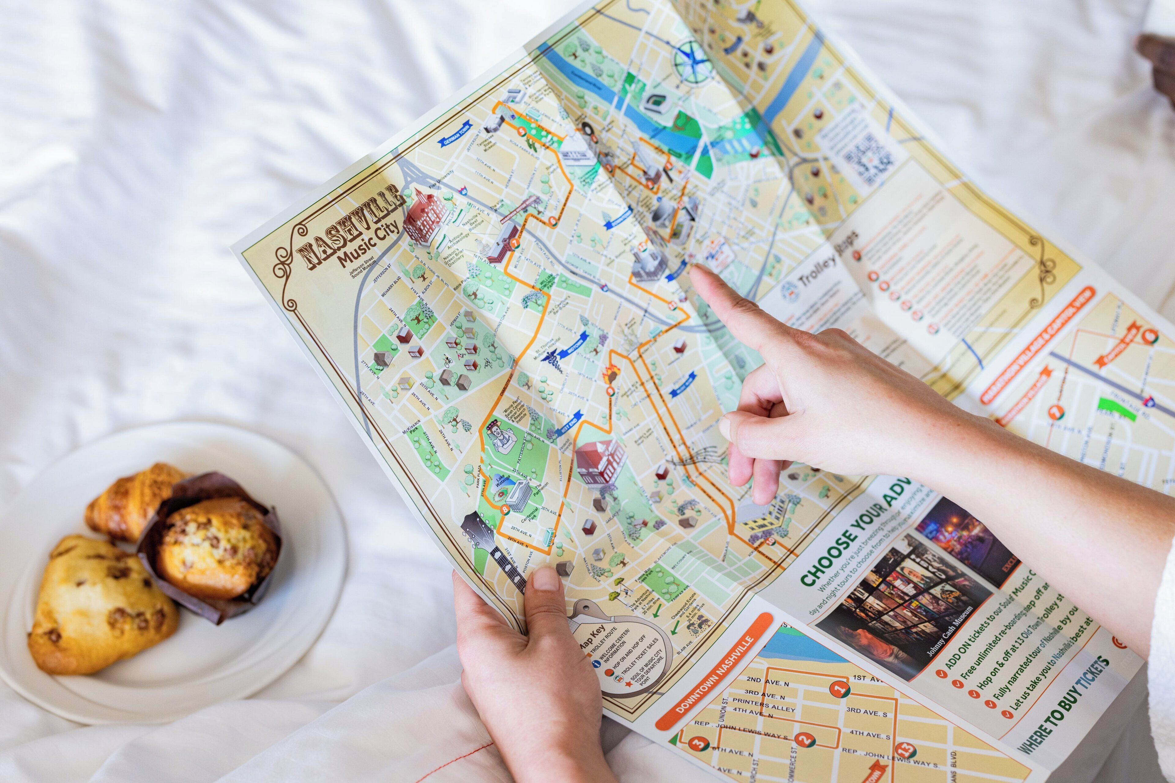Une personne tient une carte de Nashville, et sur la table, on peut voir une assiette de pâtisseries et un billet.