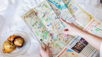 A person holding a map of Nashville, with a plate of pastries and a ticket on the table.