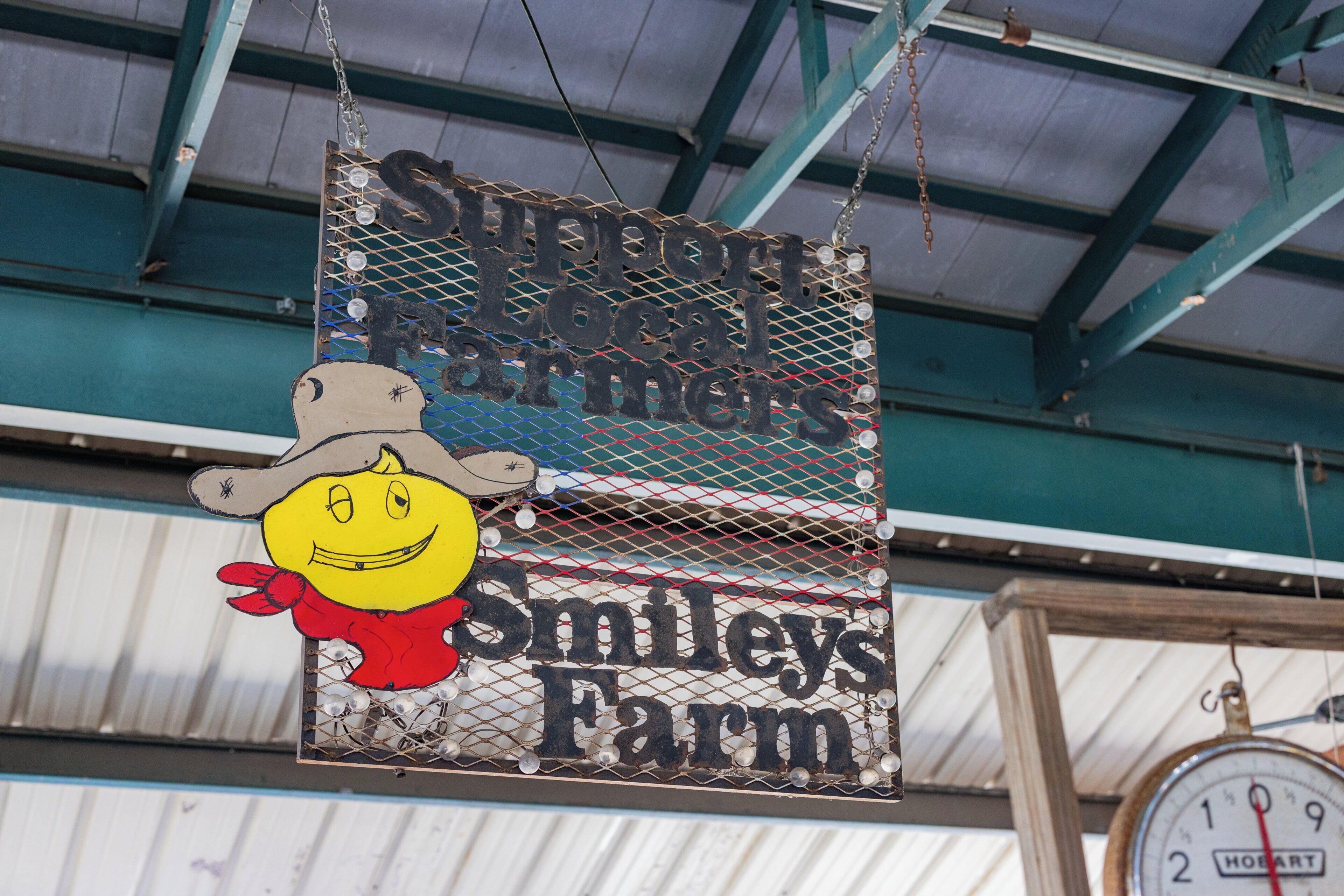 Een hangend bord met een cartoonfiguur en de tekst 'Smiley's Farm'.