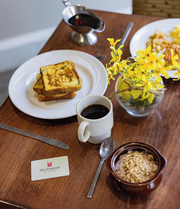 Bandeja de desayuno con tostadas, café, flores y cereales.