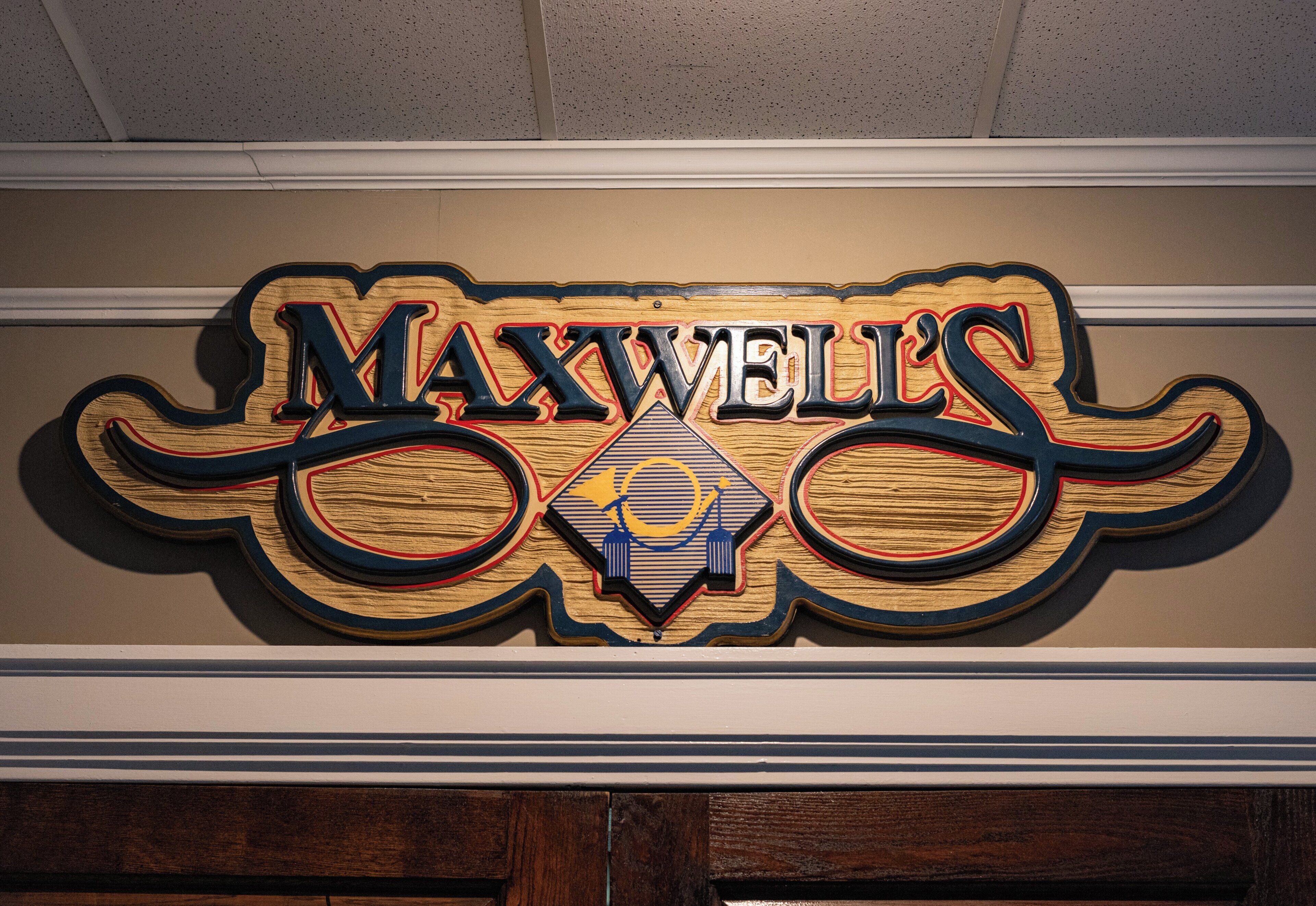 A wooden sign with the name 'MAXWELLS' in stylized lettering.