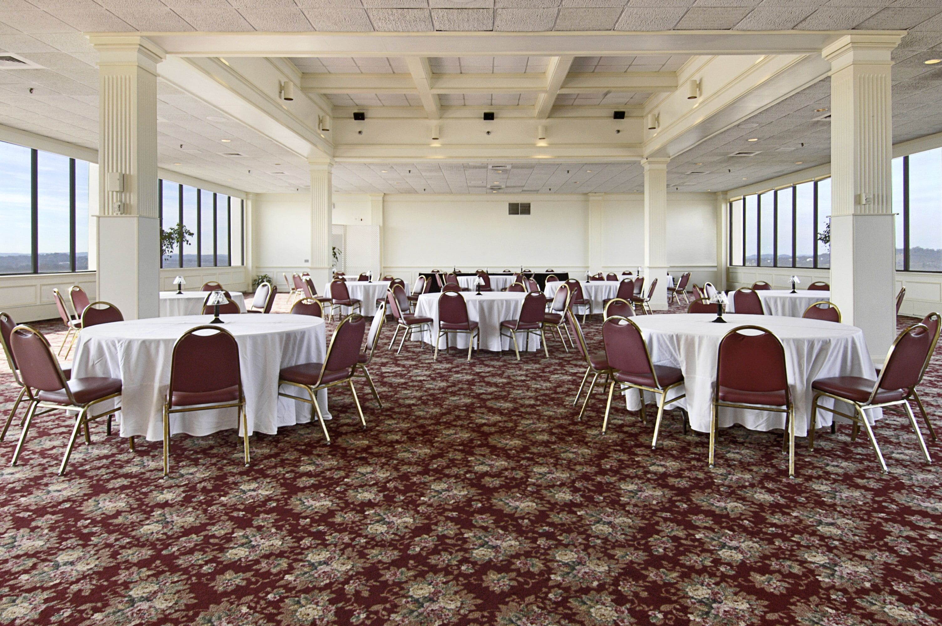 Une salle de conférence avec des tables rondes, des chaises et un sol recouvert de moquette.