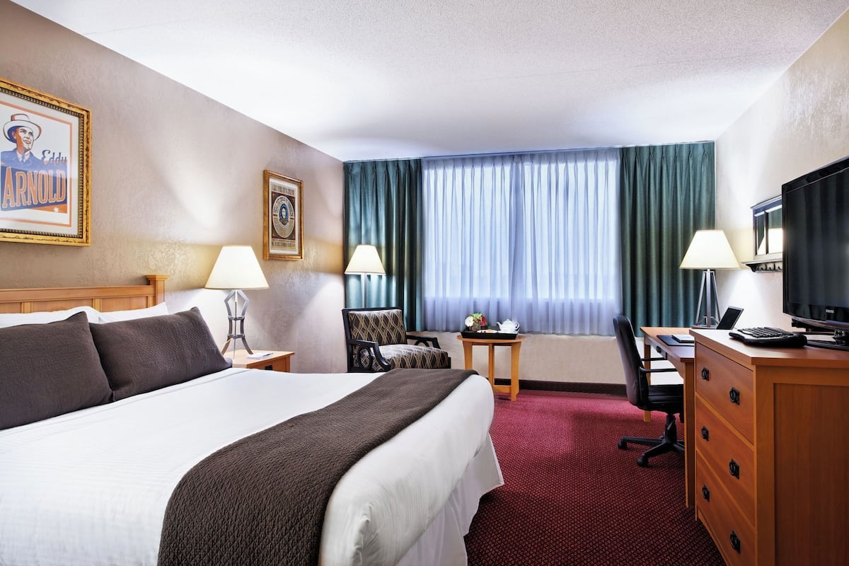 Ein Hotelzimmer mit Bett, Schreibtisch, Fernseher und Vorhängen.