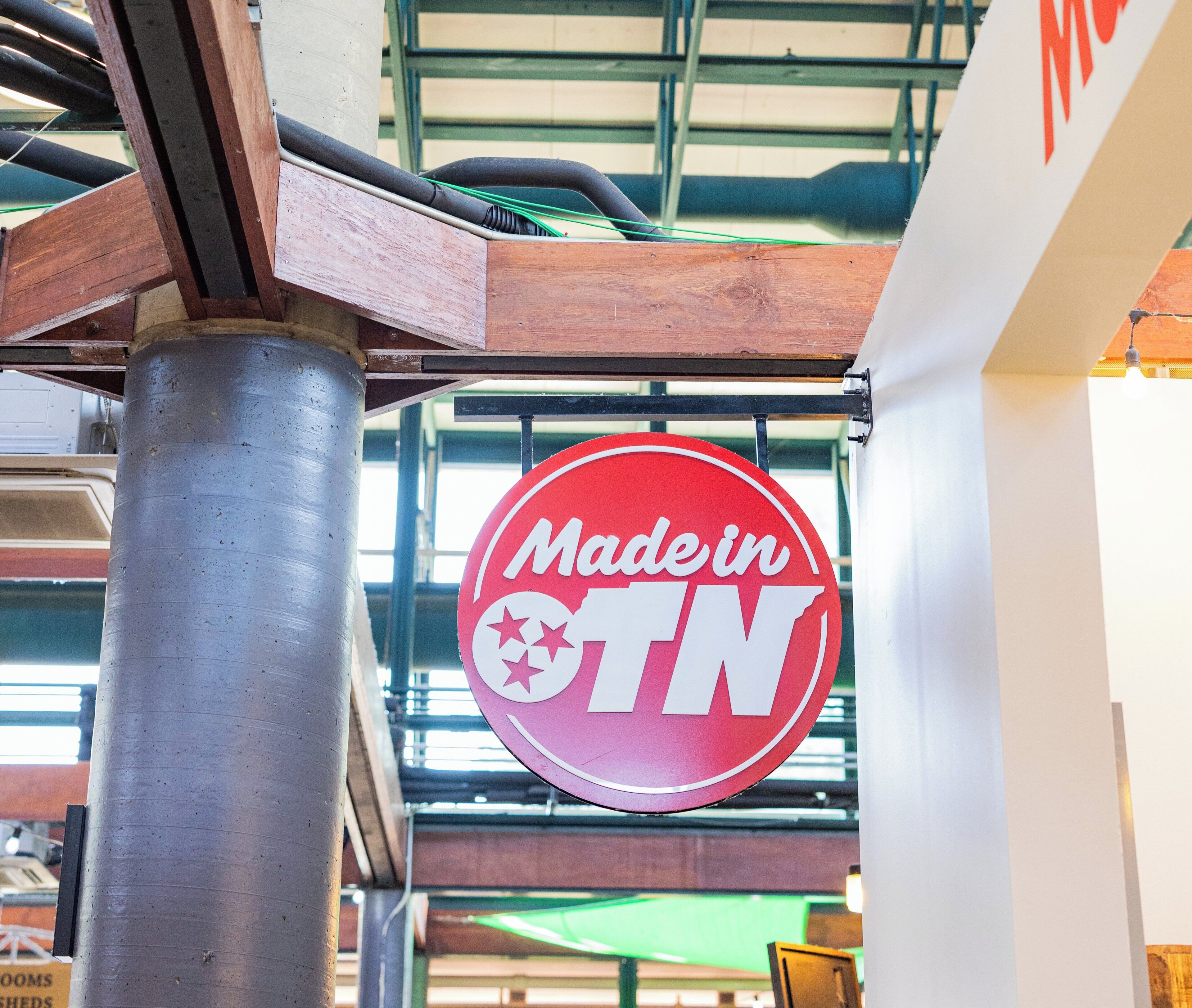 Una señal circular con el texto 'MadeinTN' colgado de una estructura metálica.