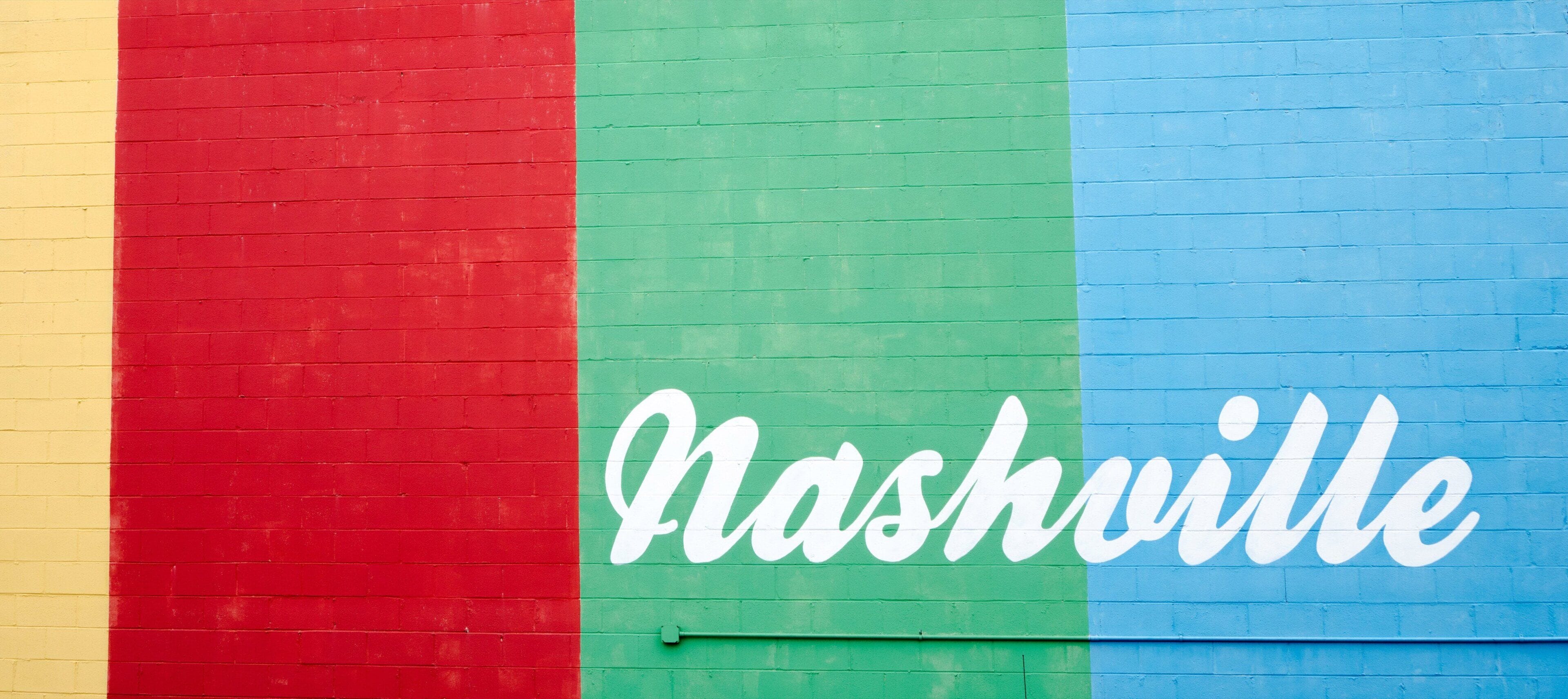 A wall with vertical stripes in red, green, and blue, and the word 'Nashville' written in white cursive letters.