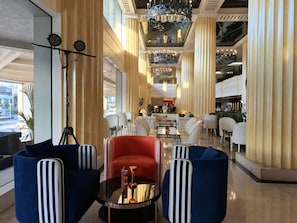 Un hall de hotel con zona de estar, un bar y vistas a la calle.