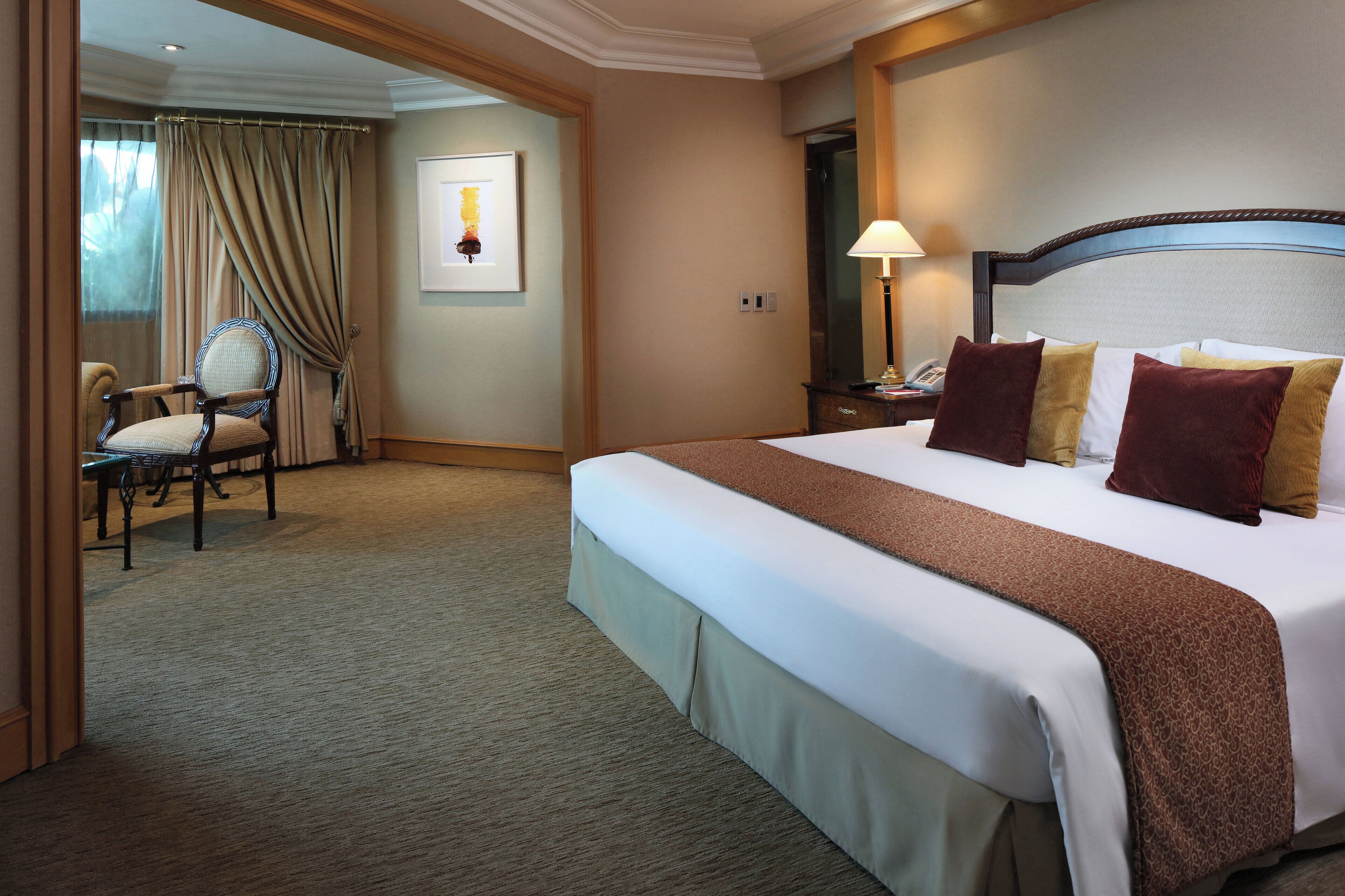 Une chambre d’hôtel avec un grand lit, une chaise, un bureau et une fenêtre avec des rideaux.