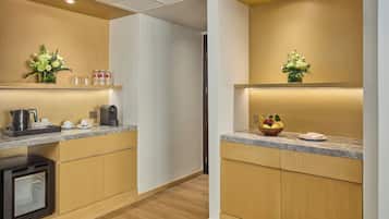 Une cuisine moderne avec des meubles en bois, des plans de travail en marbre et des appareils électroménagers intégrés. On peut y admirer des compositions florales sur les étagères et un panier de fruits sur le plan de travail.