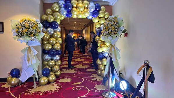 Un pasillo decorado con un arco de globos y arreglos florales.