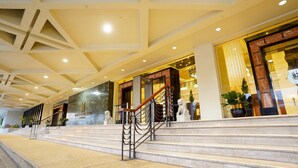 Un vestíbulo de hotel con una escalera de mármol, una recepción y una estatua.