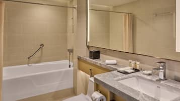 A modern bathroom with a bathtub, a sink, and a large mirror.