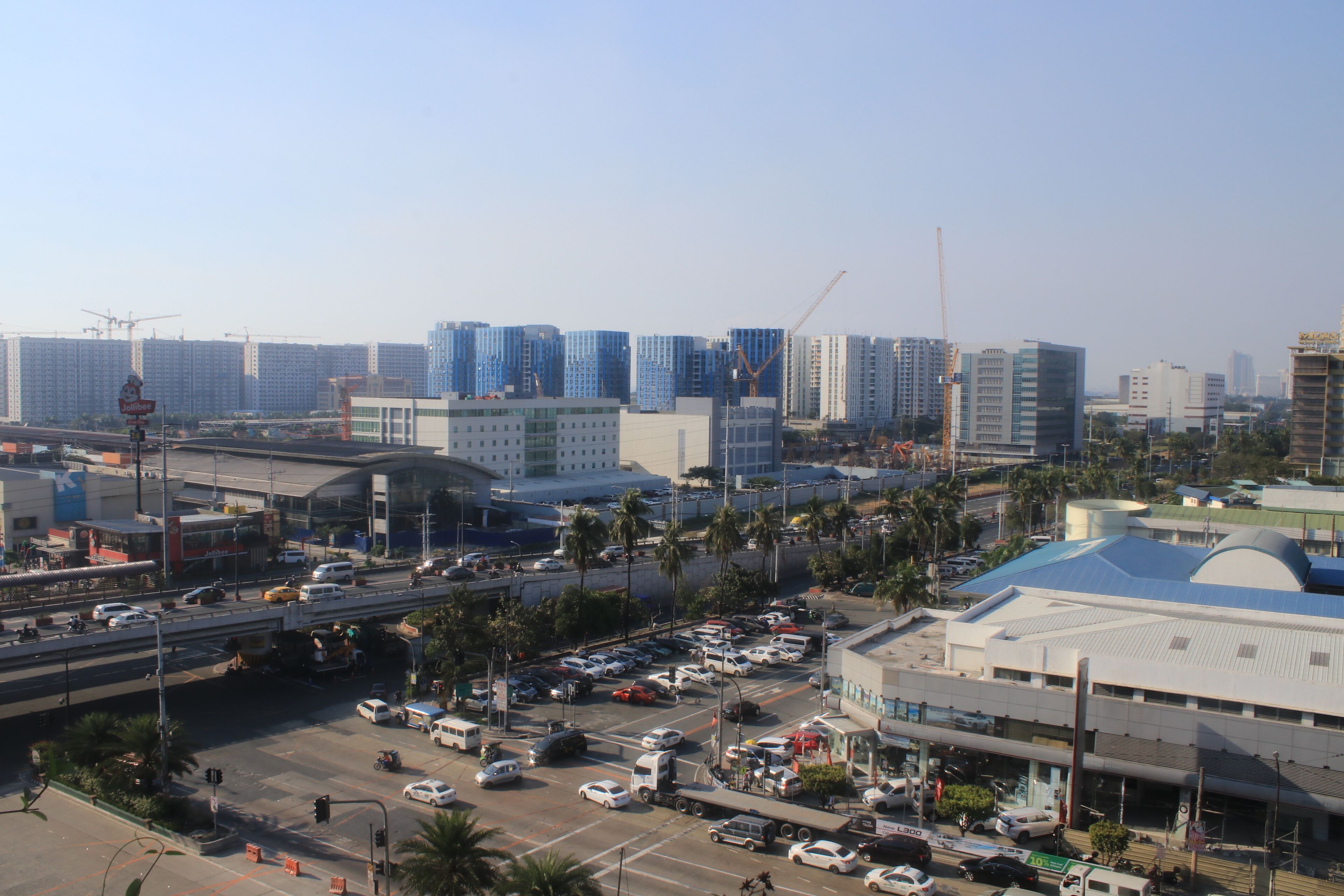 A cityscape with modern high-rise buildings, a busy intersection, and a parking lot.