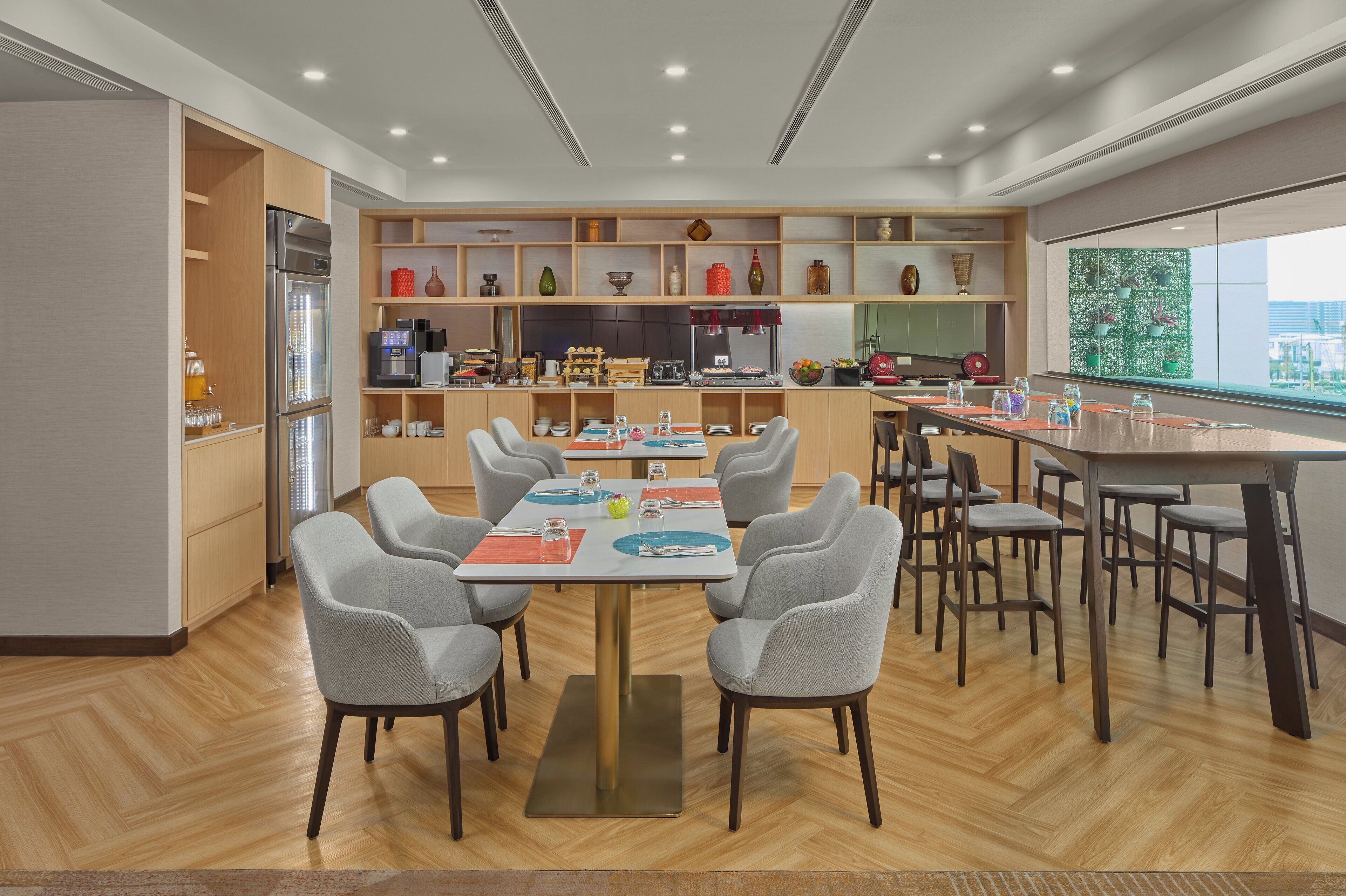 A modern kitchen with a central island, built-in appliances, and a large window offering a city view.