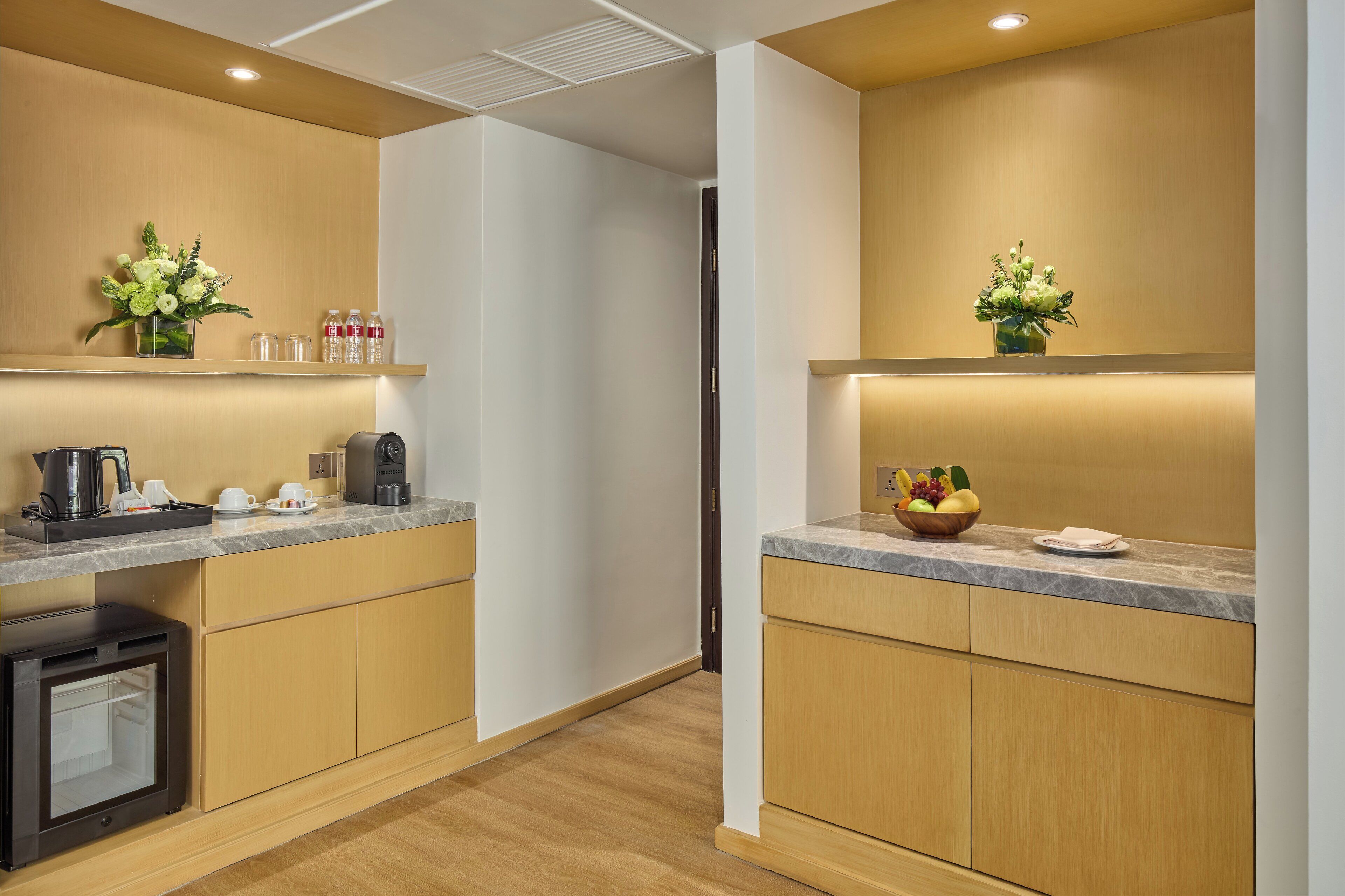 Una cocina moderna con armarios de madera, encimera de mármol, cafetera y frutero.
