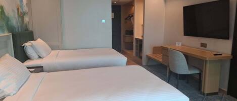 Habitación de hotel con dos camas, un escritorio, una silla, un televisor y un cuadro en la pared.