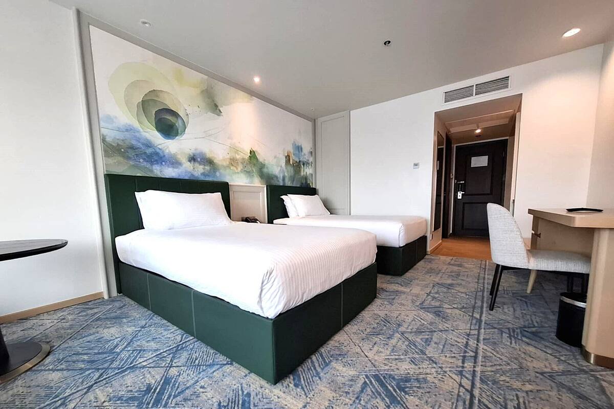 A hotel room with two beds, a desk, and a chair.